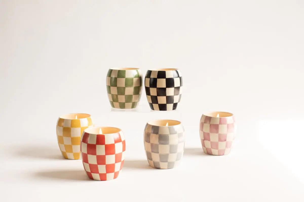 Five Rose + Santal - Checkmate Candle 11 oz pieces in reusable containers, each with a unique checkerboard pattern in yellow, green, black, gray, and red, are arranged on a plain background.