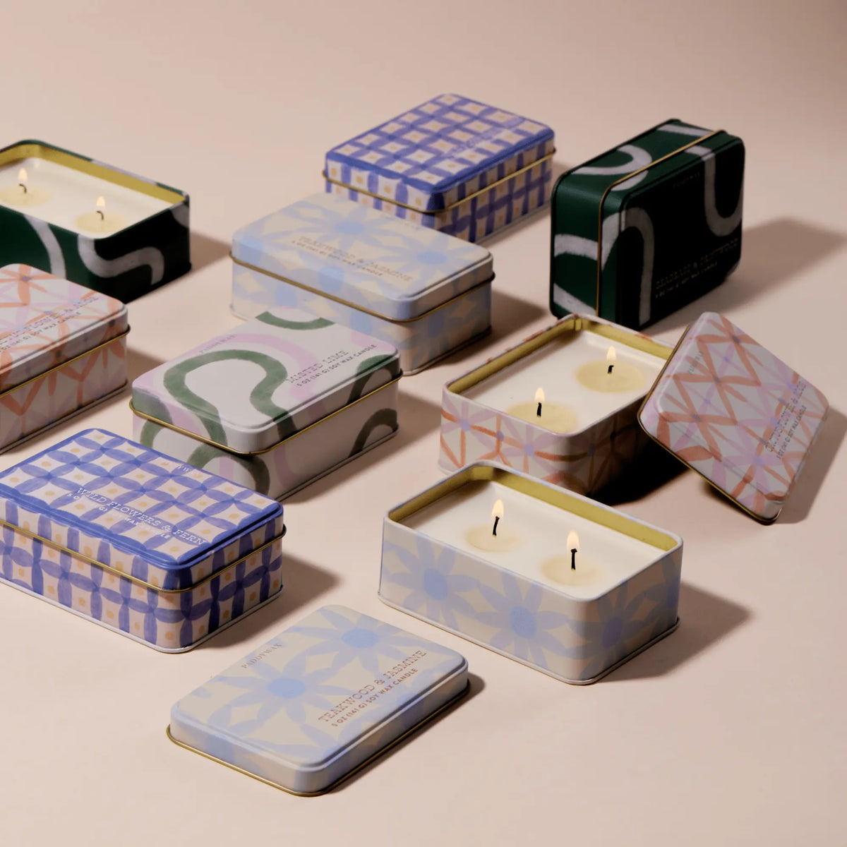 Cactus Flower & Aloe - 5 oz Tin Candles, featuring rectangular patterned tins, are displayed on a neutral surface. Some tins are open, showing the cream-colored candle and multiple wicks inside.
