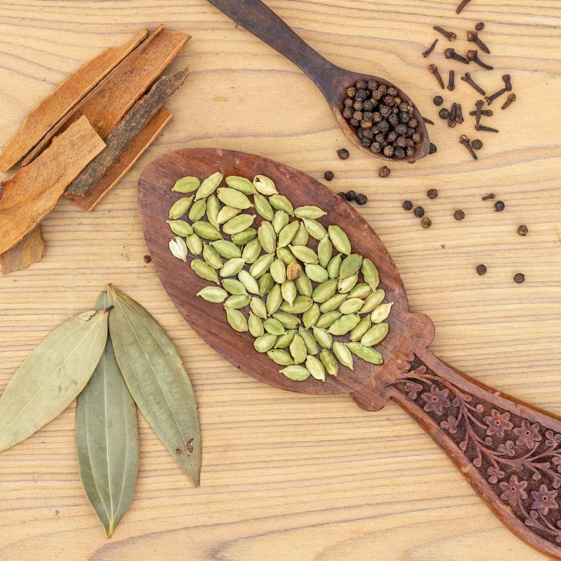 wooden spoon full of light green cardamom pods
