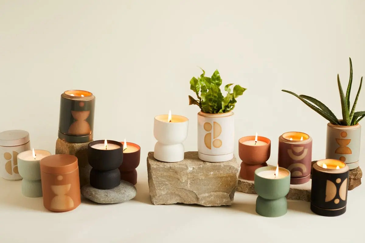 A Wild Fig & Vetiver - Form 6 oz Candle in a geometric-patterned ceramic container displayed among rocks against a plain background.