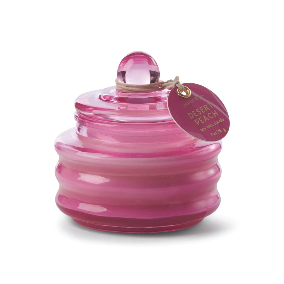 A pink, round, ribbed glass jar candle with a matching lid and tag labeled Desert Peach - Beam 3 oz Candle—ideal for bringing warm ambient light to any room.