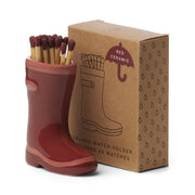 The Wellington Boot Matches - Dark Red features a red ceramic boot match holder filled with matches, displayed beside its illustrated brown cardboard box—a charming home decor gift.