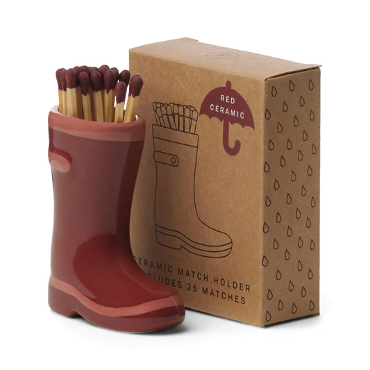 The Wellington Boot Matches - Dark Red features a red ceramic boot match holder filled with matches, displayed beside its illustrated brown cardboard box—a charming home decor gift.
