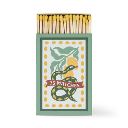 A Dopo "Snake" - 75ct Boxed Matches: Safety matches with yellow tips in a box featuring a green and yellow snake wrapped around a "75 MATCHES" banner, accented by green leaves and yellow dots. The perfect match for your A Dopo candle.
