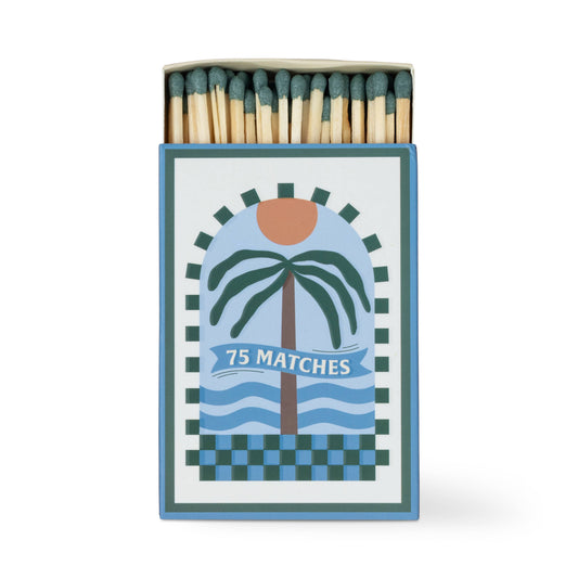 The A Dopo "Palm Tree" 75ct Boxed Matches feature a Mediterranean-inspired design with a palm tree, sun, and waves. Each box contains 75 wooden matches with green tips—ideal for lighting your A Dopo candle.