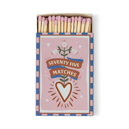 The A Dopo "Hearts" 75ct Boxed Matches feature a pink, blue, and white box adorned with a heart, flowers, and ribbon. Pink-tipped safety matches add charm to your candle setup or as a Mediterranean-inspired keepsake.