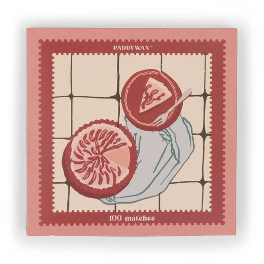 The Picnic & Pie - Peach Matches is a pink and red matchbox featuring 100 matches and an illustration of a hand holding a grapefruit half on a tiled background.