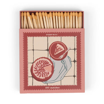 An open box labeled “Picnic & Pie - Peach Matches” reveals wooden matches inside, featuring an illustration of two halved pomegranates on a tiled background.