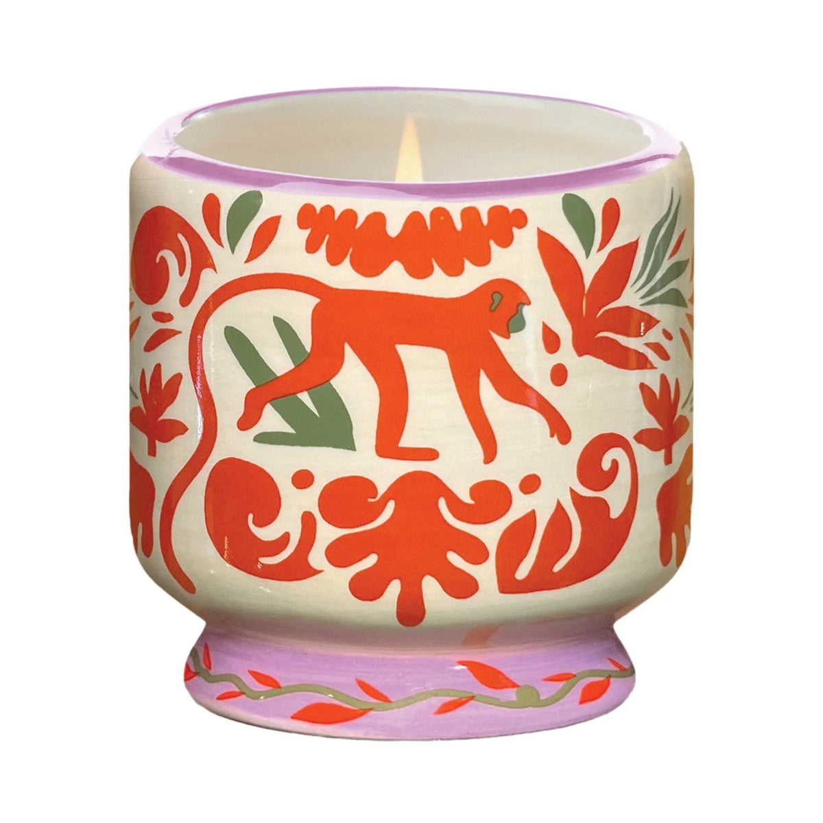 The Coconut & Amber - A Dopo 8 oz Candle comes in a lit ceramic holder with red and green animal and leaf patterns, featuring a central red monkey—perfect for fans of bold fragrance candles.