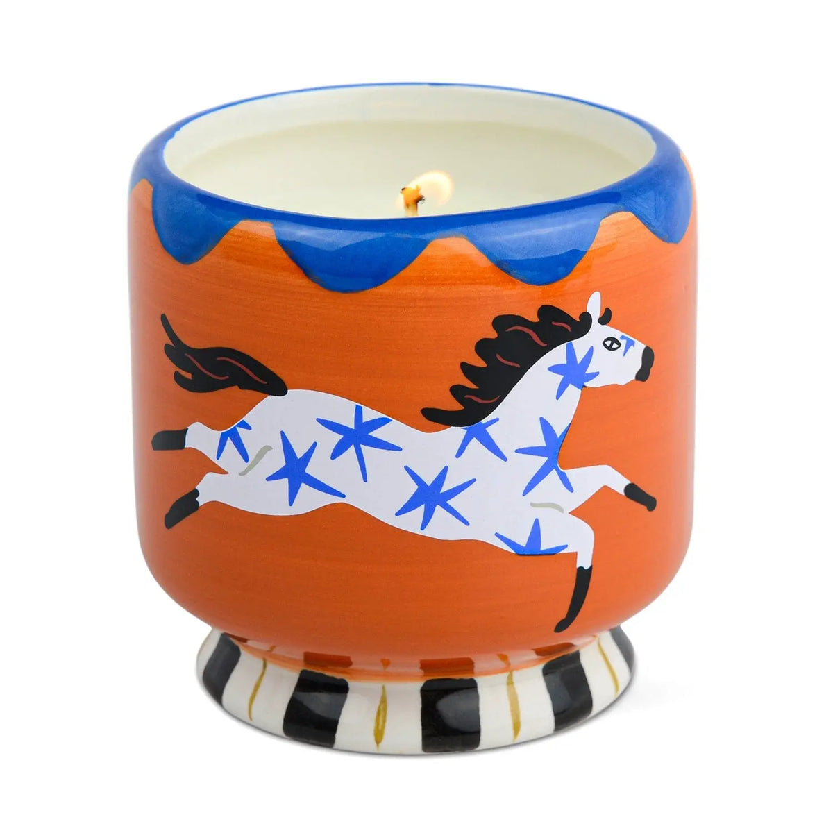 Introducing the Sienna Sunset - A Dopo 8 oz Candle: A decorative scented candle housed in an orange ceramic vessel adorned with a white horse featuring blue stars, a black mane and tail, and a striking blue rim. The base boasts a bold black and white striped pattern, making this eye-catching candle a standout addition to any space.