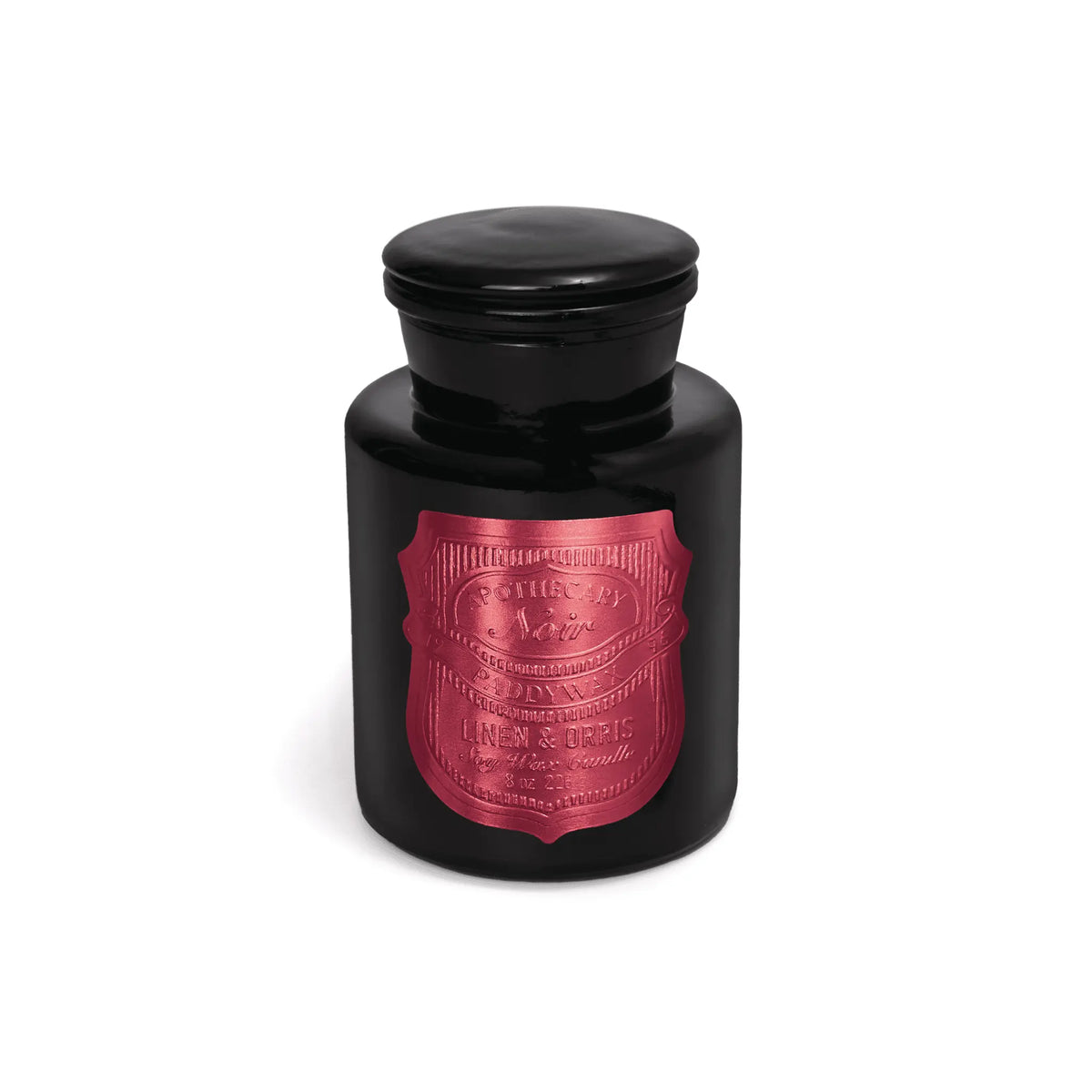 The Linen & Orris - Apothecary Noir 8 oz Candle is a black glass apothecary candle with a round lid and a metallic red label featuring decorative text on the front, displayed against a white background.