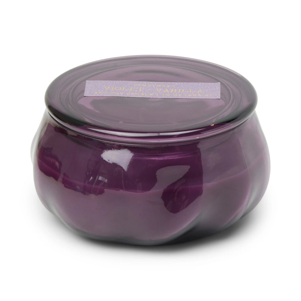 A round, amethyst glass jar candle with a matching lid, the Violet & Vanilla - Basalt 10 oz Candle features a rectangular label on top indicating its Violet & Vanilla scent. This scented candle boasts a smooth, glossy surface that enhances its elegant appearance.