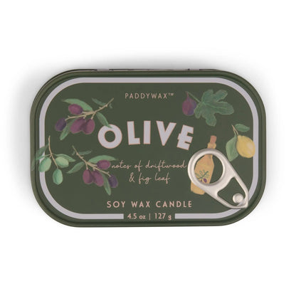 A green tin candle from the Bistro Collection, labeled "Fig & Olive - Bistro 4.5 oz Tin Candle," features illustrations of olives, fig leaves, a lemon, and a bottle on its pull-tab lid. This scented soy wax candle offers notes of driftwood and fig leaf.