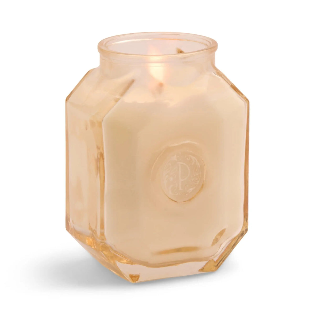 The Cotton + Teak - Botanica 8 oz Candle features a light hue and burns in a faceted glass jar with a decorative emblem, adding luxury and refined fragrance to your space.