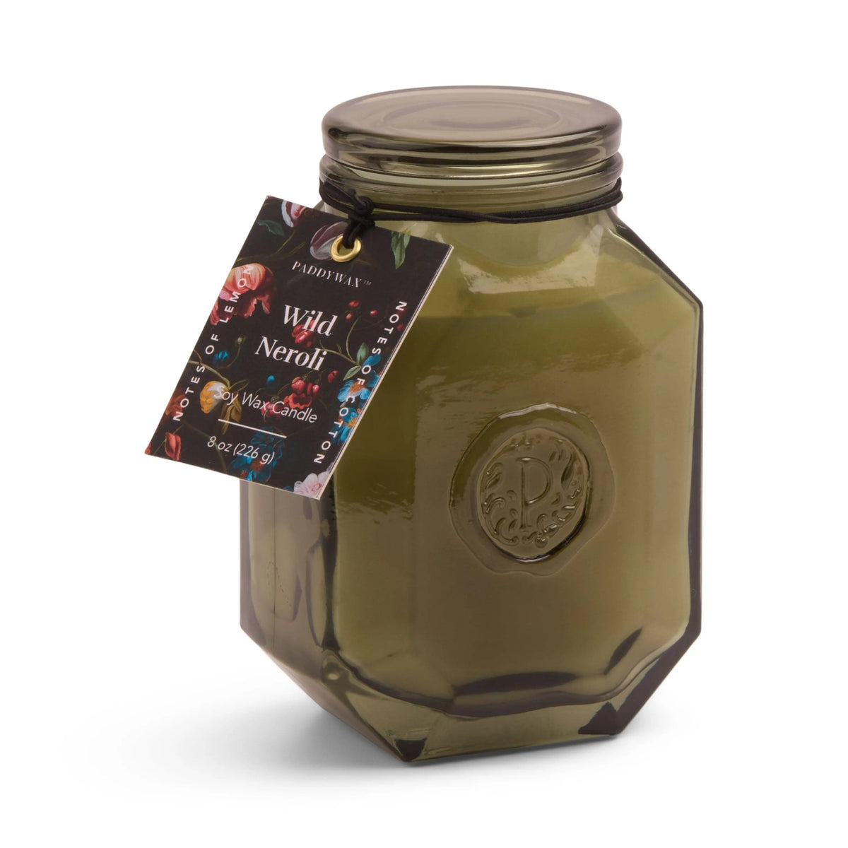 The Wild Neroli - Botanica 8 oz Candle comes in a green octagonal glass jar with a lid and floral tag, offering a fresh home fragrance experience.