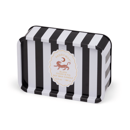 The Black Cedar & Fig - A Dopo 6.5 oz Tin Candle features bold black and white stripes and a round center label—this Mediterranean-inspired soy wax candle is perfect for travel or any adventure.