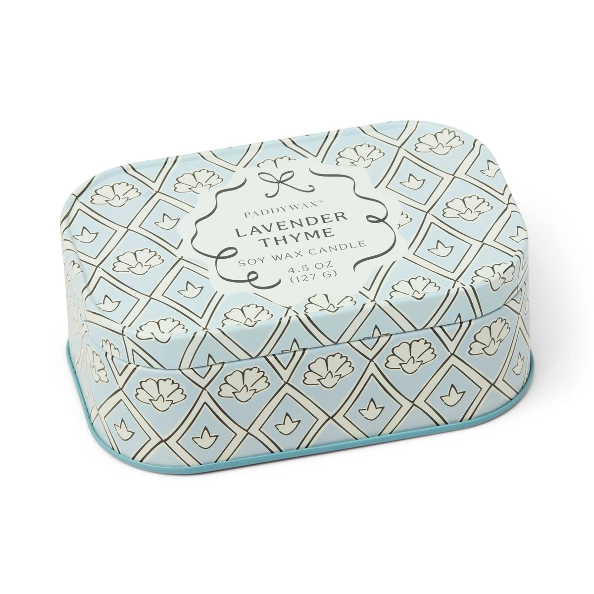 A rectangular tin candle labeled “Lavender & Thyme - Chérie 4.5 oz Tin Candle”, featuring a blue and white floral pattern with rounded edges and a decorative geometric design. The beautifully scented candle is perfect for adding a touch of tranquility to any space.