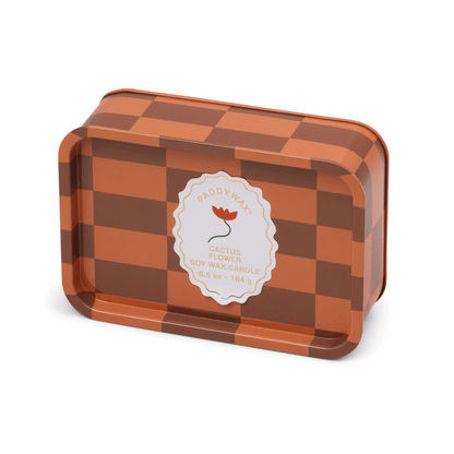 The Cactus Flower - A Dopo 6.5 oz Tin Candle features a rectangular tin with a brown and orange checkered design, white circular label, and red flower illustration—ideal for fans of bold fragrances in stylish tins.