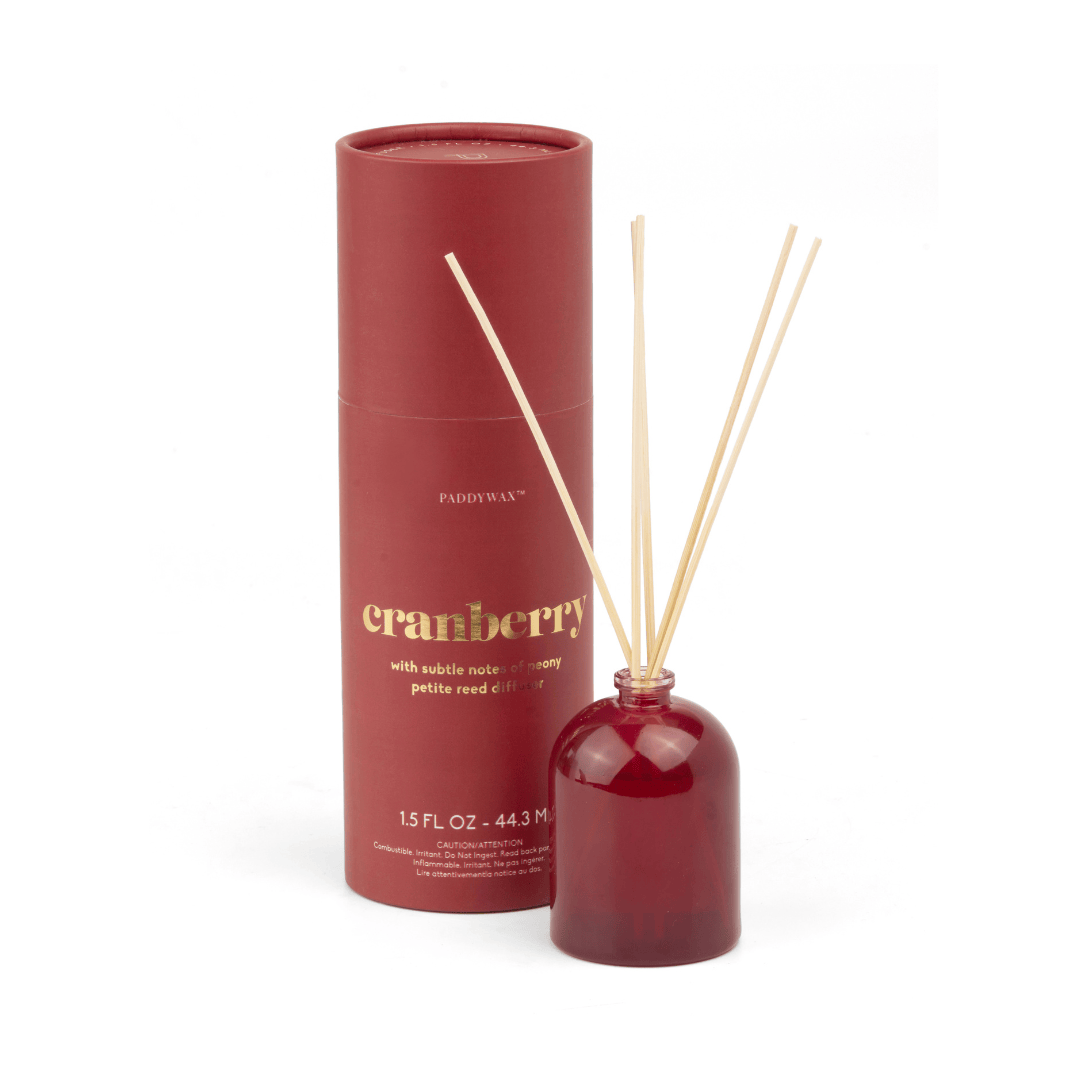 A Cranberry - 1.5 oz Diffuser features a red cylindrical container paired with a matching diffuser bottle and wooden reeds, making it a stylish, giftable home fragrance set.