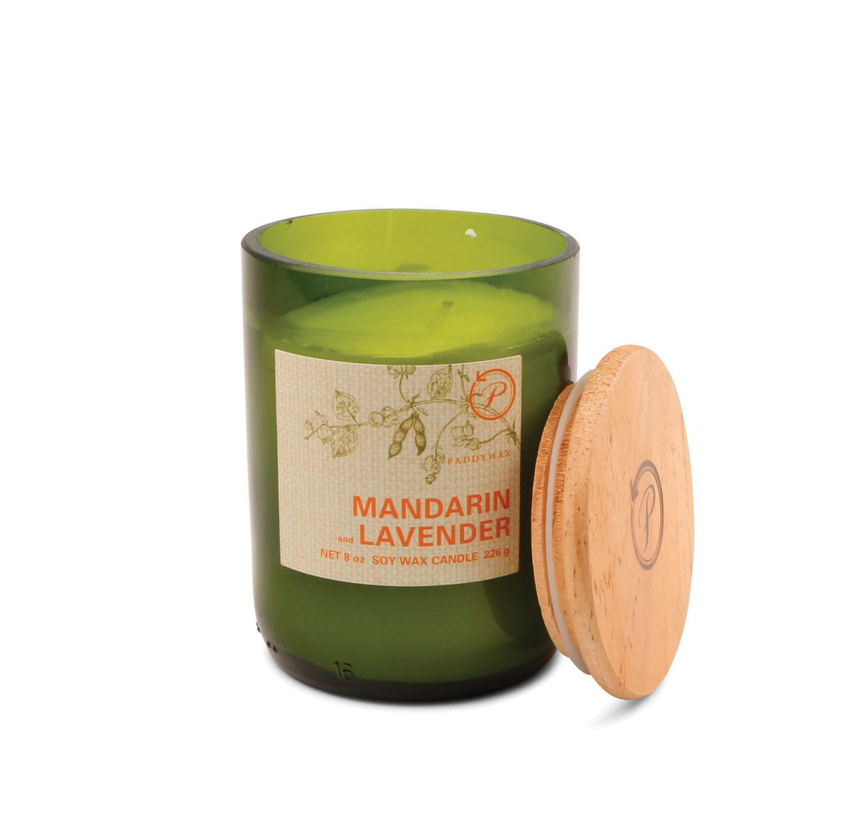 A Mandarin + Lavender - Eco 8 oz Candle in a green glass jar with a wooden lid sits nearby. Its label, adorned with botanical illustrations and product info, makes it an ideal sustainable candle choice for eco-conscious living.
