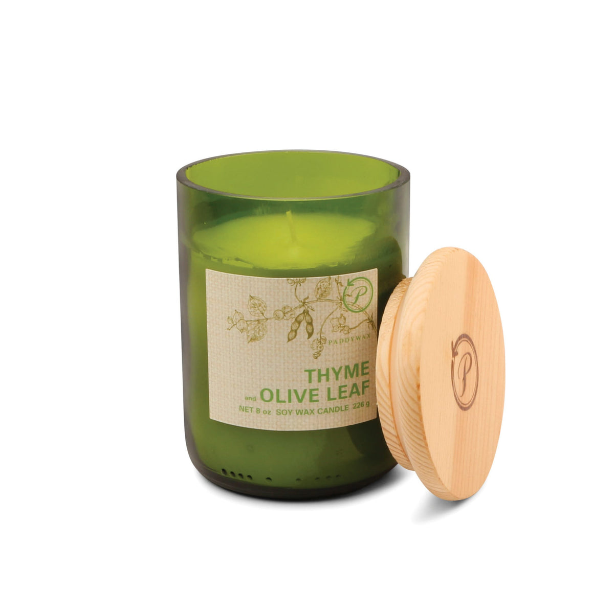 The Thyme + Olive Leaf - Eco 8 oz Candle is a green glass jar with botanical illustrations and a wooden lid. Its light herbal fragrance comes in a recycled vessel, combining eco-friendly design with fresh, green scents.