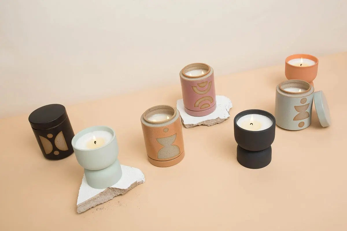 Six Wild Fig & Vetiver - Form 6 oz Candles with abstract designs are displayed on a neutral surface, some on white stone-like coasters—ideal as planter candles and a stylish decorative home fragrance for any room.