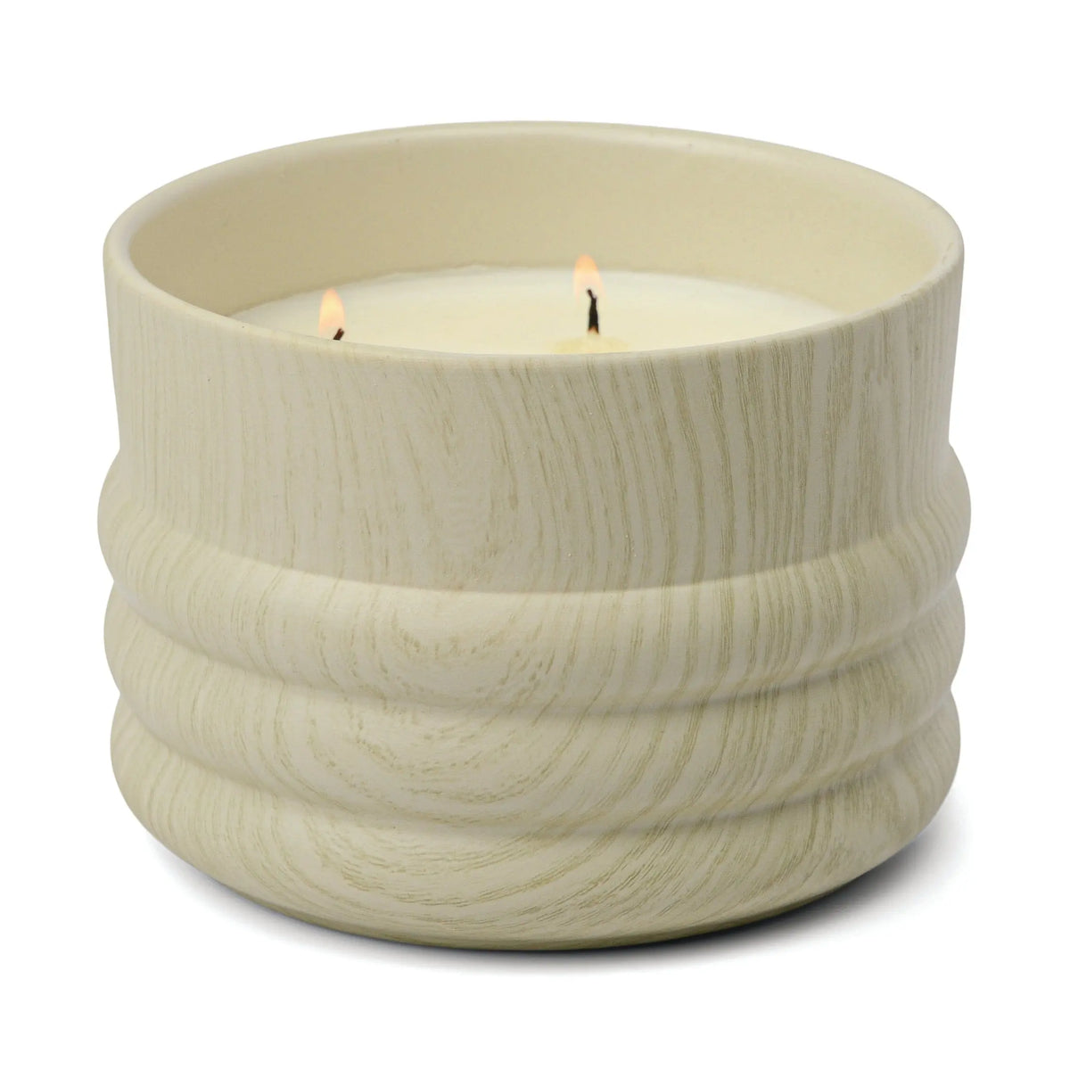A cream-colored, textured ceramic vessel from the Grain collection holds a 12 oz Hinoki Driftwood candle with two lit wicks.