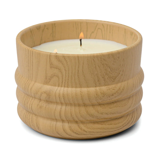 The Wild Fig & Cedar - Grain 12 oz Candle features two lit wicks in a round, light woodgrain container, ideal for those who love calming cedar and wild fig scents.