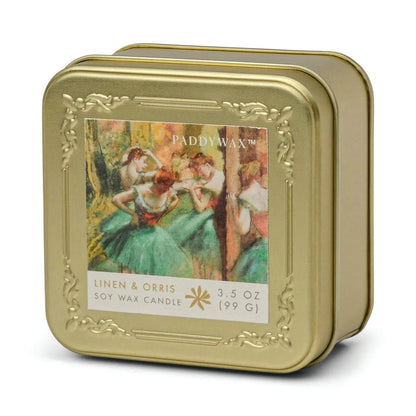 The Degas French Linen + Orris - Impressionist 3.5 oz tin candle comes in a gold metal tin featuring ballet dancers in green tutus, inspired by impressionist art. This Paddywax candle offers an elegant, art-inspired fragrance experience.