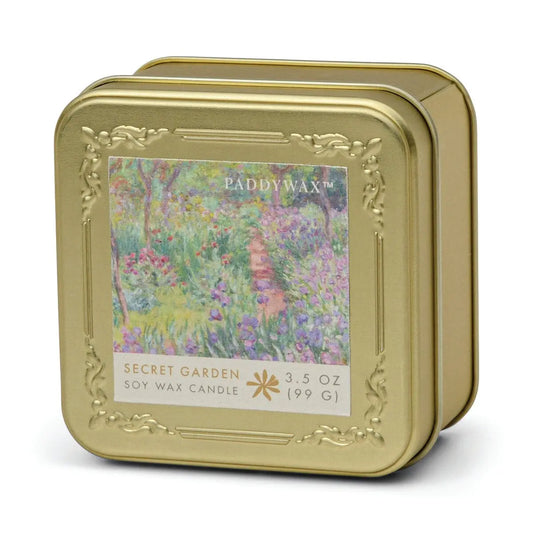 A gold tin with an embossed frame features a colorful garden path on the label, reading "Claude Monet Secret Garden - Impressionist 3.5 oz Tin Candle.
