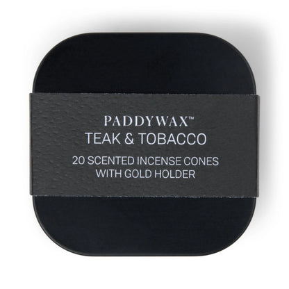 A black tin labeled “Teak & Tobacco - Metal Incense Tin” is shown from above, wrapped with a textured paper band. This set features one of Paddywax’s best-selling fragrances and includes a gold holder for effortless incense enjoyment.