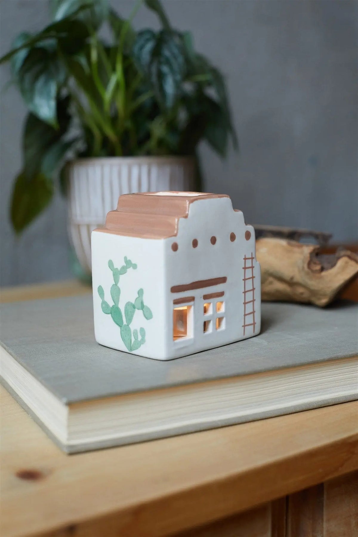 The No. 03 The Santa Fe Adobe - Incense & Tea Light Holder is a white ceramic piece shaped like a Southwestern adobe house with cactus and ladder details, ideal for adding unique adobe house decor to your space.