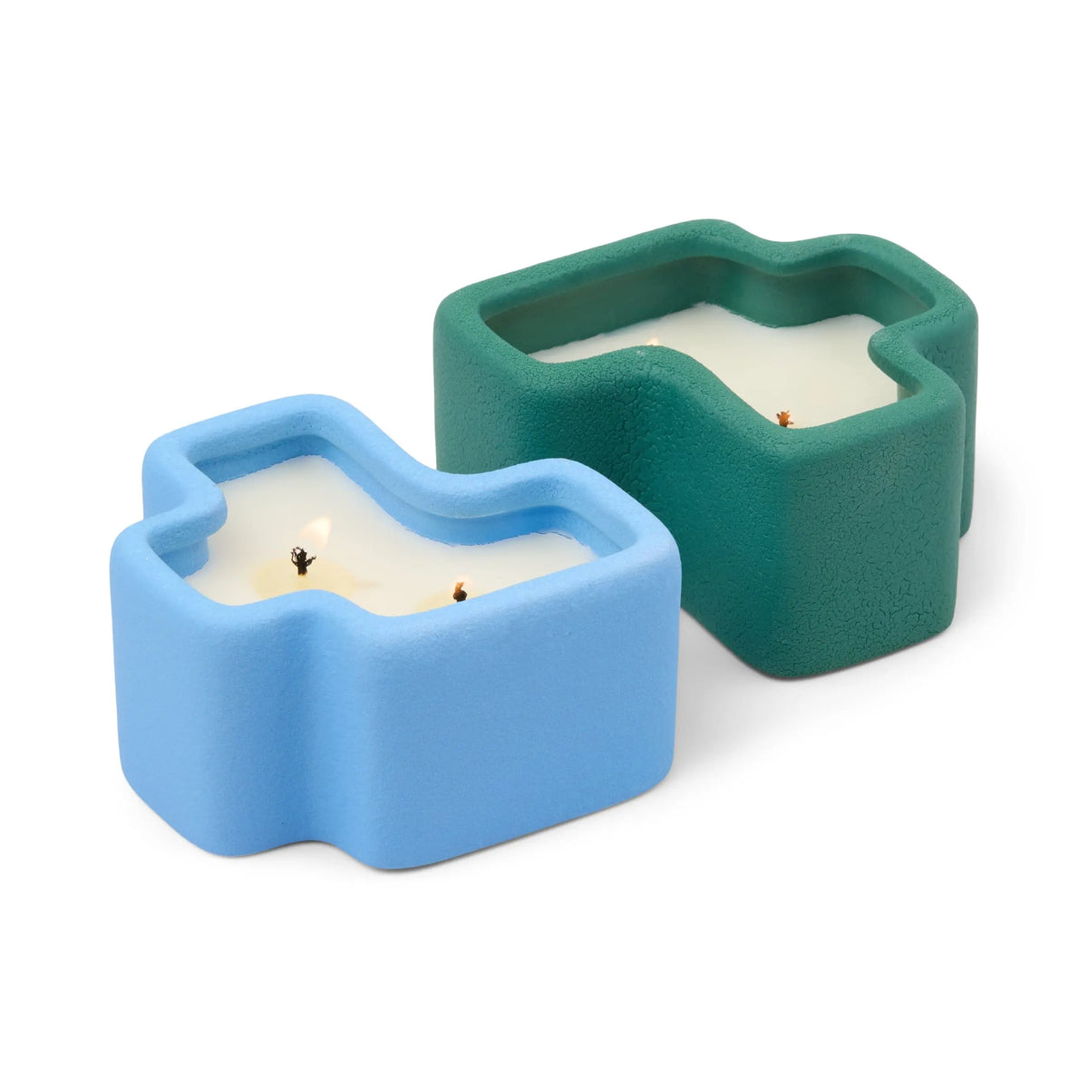 Two abstract, irregularly shaped candles in textured ceramic holders—one in light blue and the other in dark green—both with visible wicks and white wax, placed side by side on a white background. The Wild Mint & Misted Lime - Jigsaw 4 oz Candle Boxed Set features the refreshing scents of Misted Lime and invigorating Wild Mint to elevate any space.