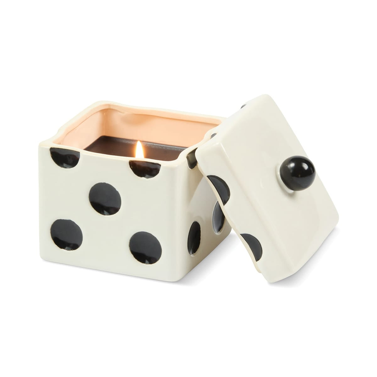 A lit Lava Stone - Lucky Dice 10 oz Candle in a white, limited-edition ceramic dice jar with black spots and a matching lid leaning against the side.
