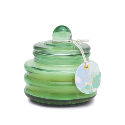 The Cactus Flower - Beam 3 oz Candle is a green glass jar with a rounded lid and knob, featuring a white string tag—an ideal gift candle offering a fresh springtime scent.