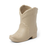 Introducing the Bergamot & Mahogany - Nashville Boot 6 oz Candle—a beige ceramic cowboy boot with decorative details, pictured against a white background. This Nashville-inspired accent is perfect for fans of western décor and unique cowboy boot candles, bringing a touch of southern charm and fragrance to any space.