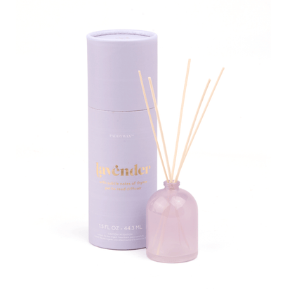 The Lavender - 1.5 oz Diffuser features a milky glass bottle with reeds and comes in a light purple cylindrical box labeled “lavender” in gold—both set against a white background, making it a perfect giftable fragrance.