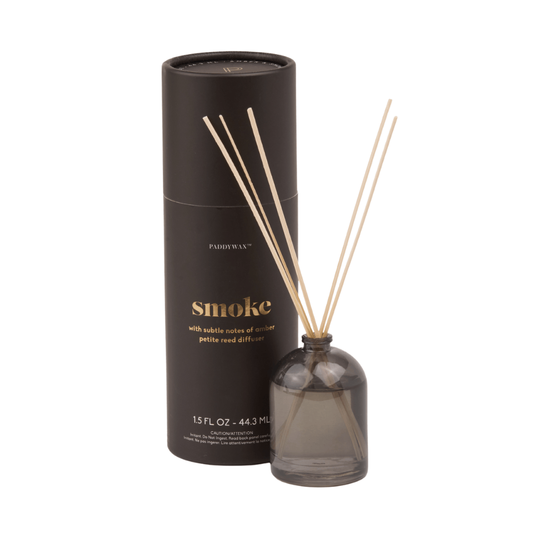 The Smoke - 1.5 oz Diffuser features a milky glass vessel with thin wooden reeds beside its cylindrical, giftable tube packaging labeled Smoke and Paddywax.