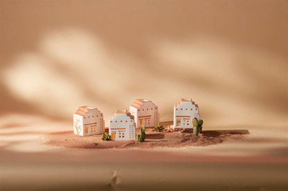 Four No. 03 The Santa Fe Adobe Incense & Tea Light Holders with pastel accents sit on sand among small cacti and plants, set against a warm beige background with soft shadows.