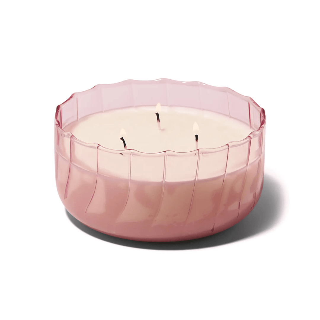 The Desert Peach - Ripple 12 oz Candle features creamy white wax with three unlit wicks in a pink ribbed glass container, displayed against a plain white background.