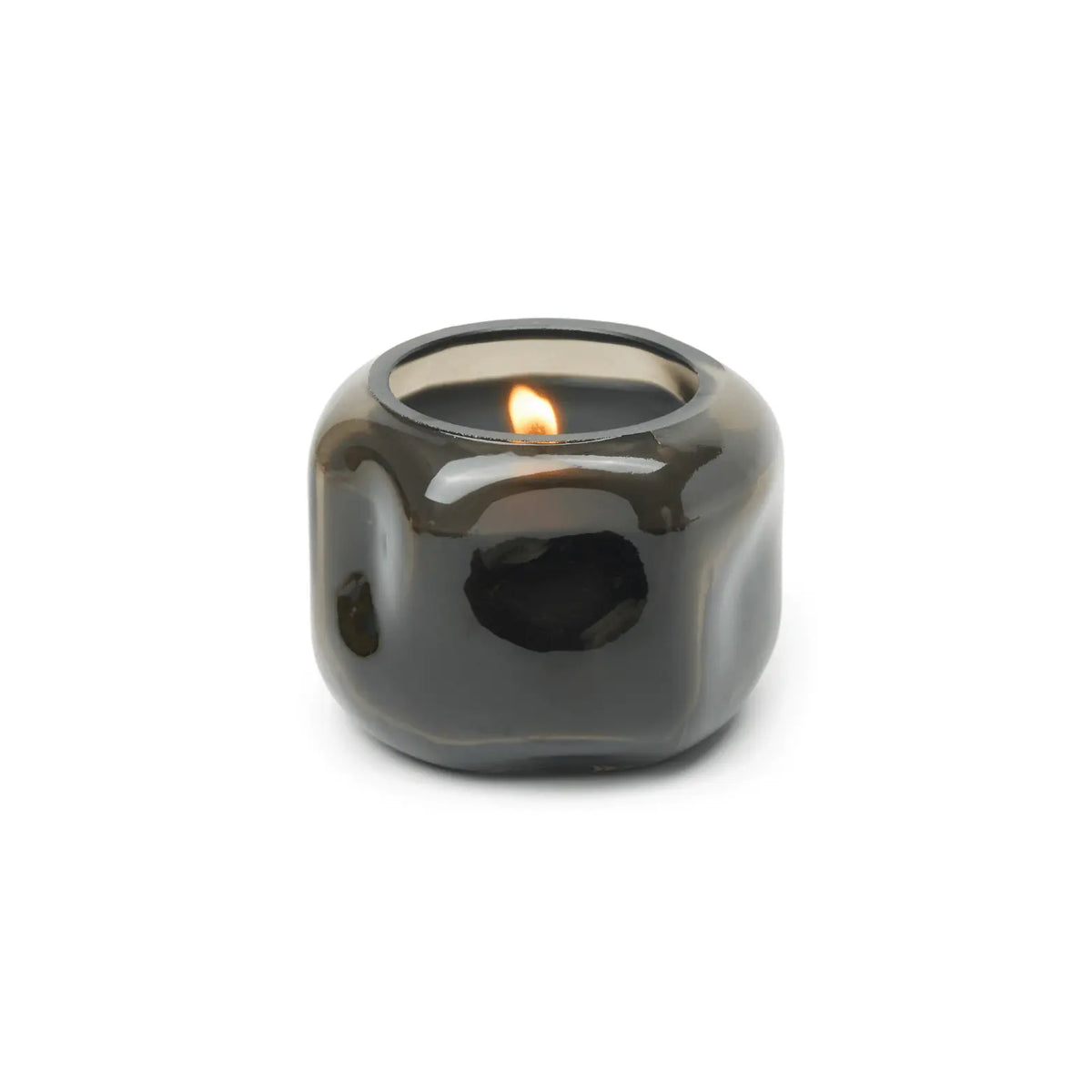 A lit Palo Santo Suede - Basalt 5 oz Candle, showcased in its glossy, round dark glass holder against a plain white background, evokes a calming ambiance with its subtle smoky wood scent.