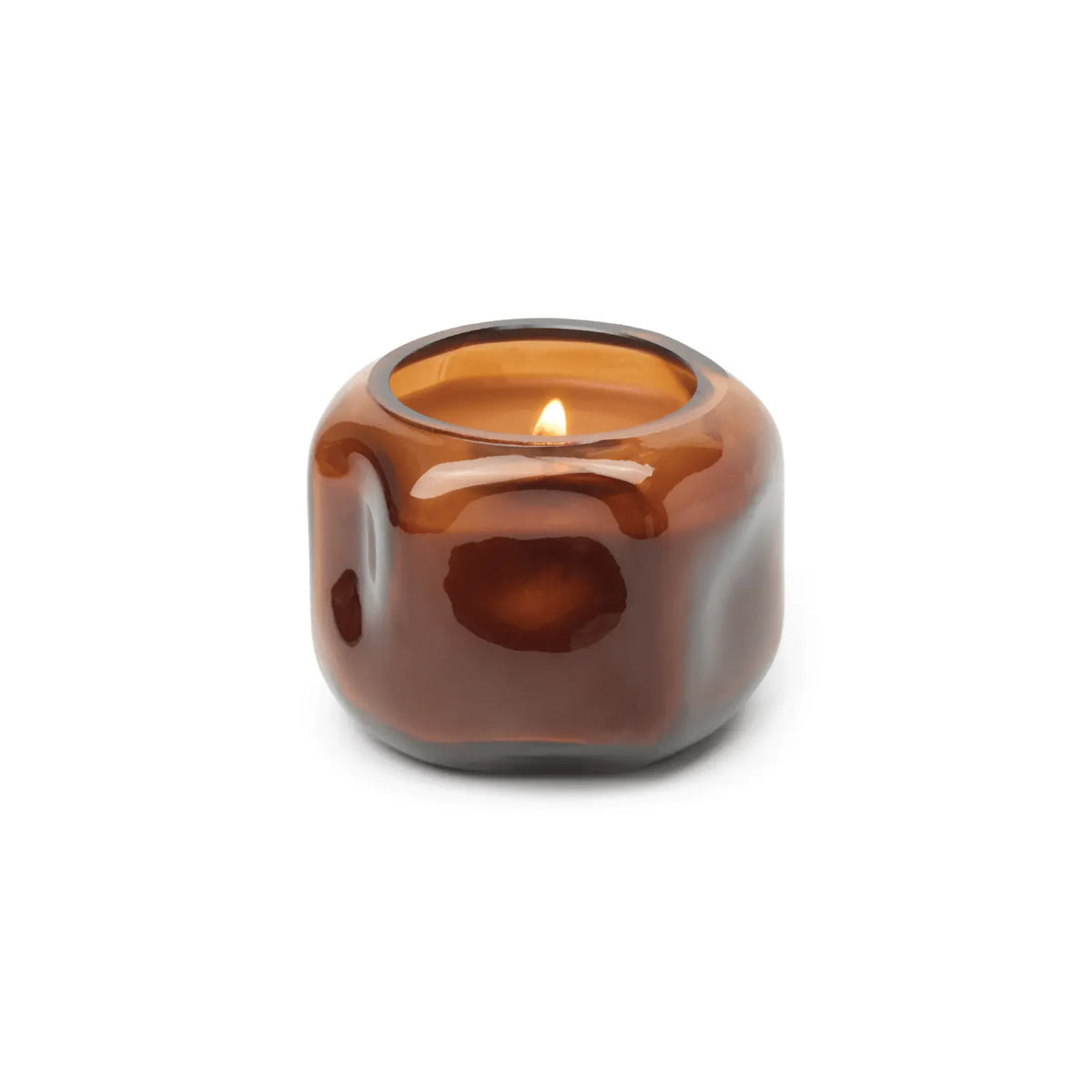 A lit Sienna Sunset - Basalt 5 oz Candle sits in a glossy, rounded, orange-rust glass holder with an irregular, organic shape, set against a plain white background.