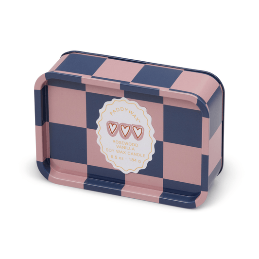 Rectangular tin candle with a pink and navy checkered pattern, labeled Rosewood Vanilla - A Dopo 6.5 oz Tin Candle. Features bold fragrance, three heart icons on the label, and decorative edges.