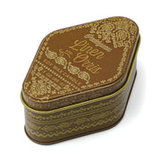 A decorative, paisley-patterned brown and gold travel-sized station tin candle labeled Linen & Orris - Station Tin 3.5oz, featuring a uniquely rounded triangular shape and a slightly askew lid—perfect for bringing warm, woody scents inspired by Northern California anywhere you go.