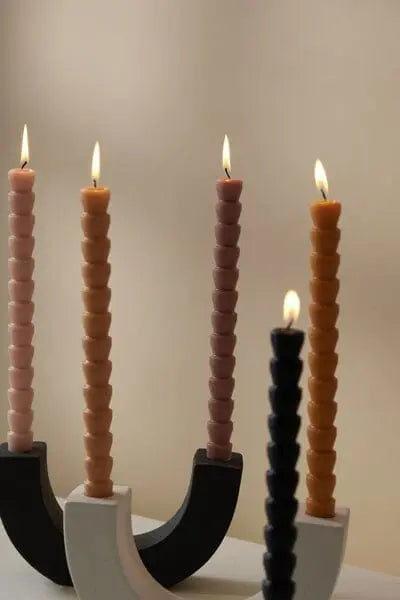 Five colorful spiral candles are lit and displayed in modern U Taper Holders - Black, set against a plain, light-colored background to add an elegant touch to minimalist decor.
