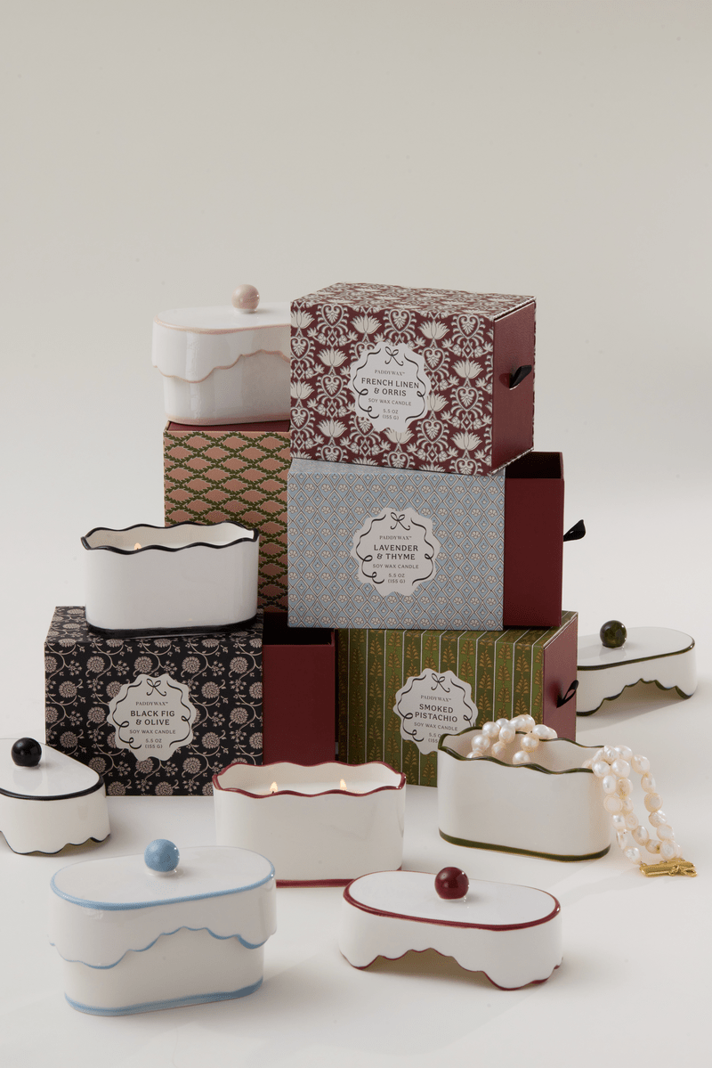 A cluster of ornate boxes sits beside Lavender & Thyme - Chérie 5.5 oz Ceramic Candle, a porcelain vessel holding a pearl necklace and hinting at delicate fragrance notes in the air.