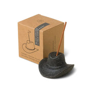 The Palo Santo Suede - Incense Holder is a black ceramic cowboy hat with an incense stick, shown next to its brown box—ideal for Nashville-inspired decor.