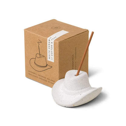 The Cotton & Teak - Incense Holder is a white ceramic cowboy hat, ideal as a Nashville gift, designed to hold a burning incense stick and comes in a box labeled "White Ceramic Cotton Hat.