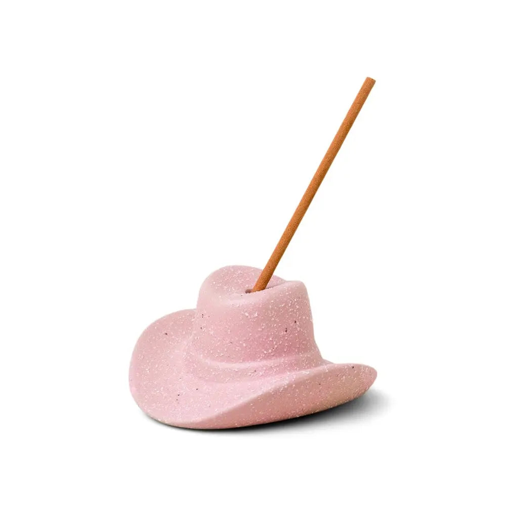 The Hinoki Wood - Incense Holder is a playful pink cowboy hat with a single incense stick inserted at an angle, blending charm and aromatic elegance.