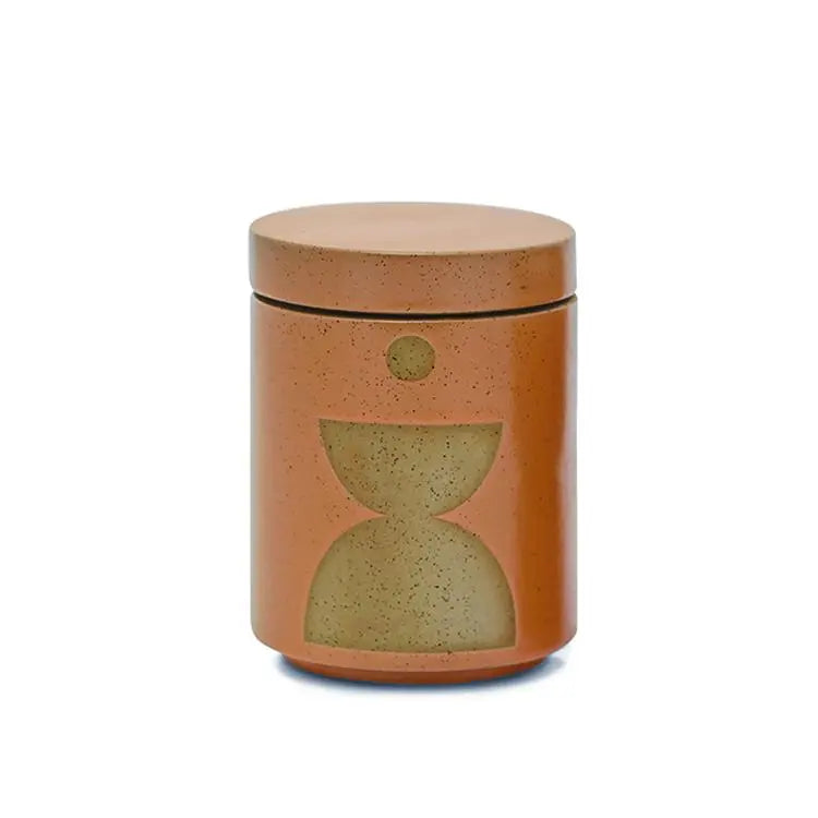 The Wild Fig + Vetiver - Form 12 oz Candle comes in a cylindrical ceramic jar with a lid, matte orange-brown finish, and geometric accents—a stylish candle holder or planter candle to elevate your home décor.